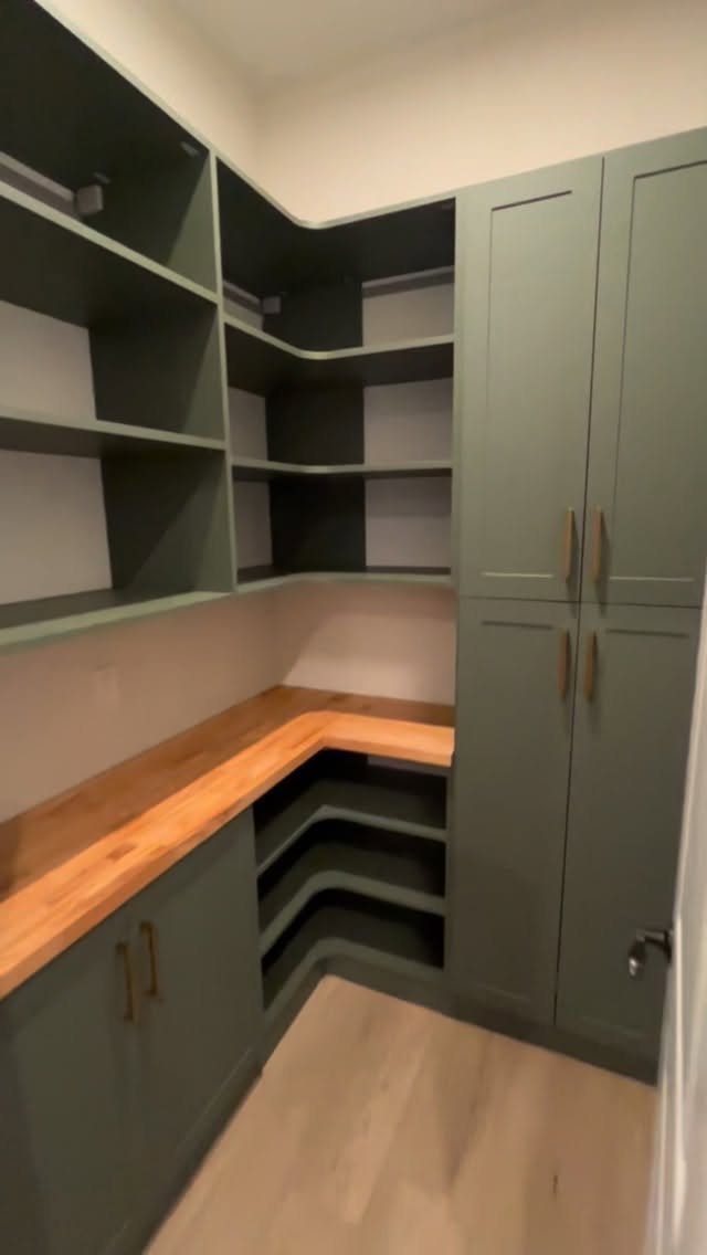 Olive green cabinets and open shelving with a light wood butcher block countertop.