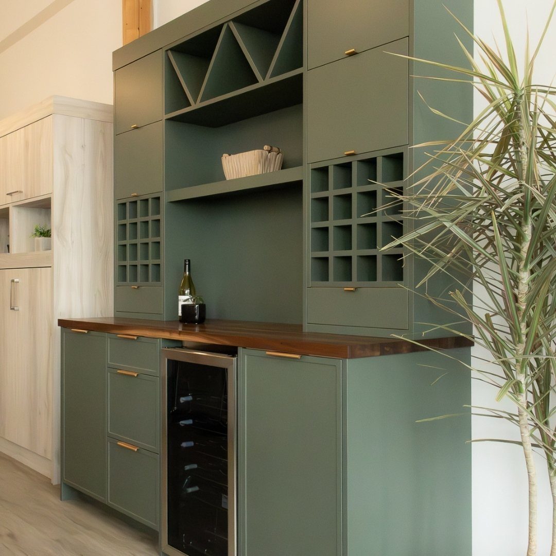 Sage green cabinets with a wooden butcher block countertop and built-in wine cooler.