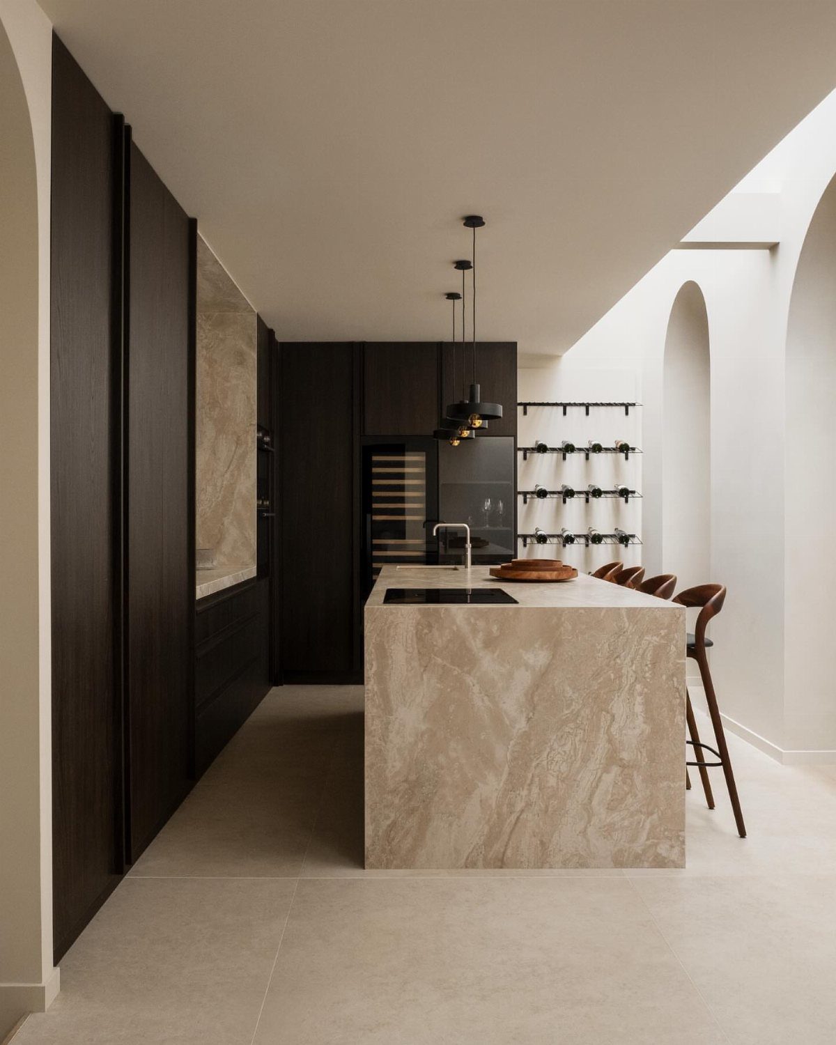 Modern luxury kitchen with a marble island, dark cabinetry, and minimalist white architecture.