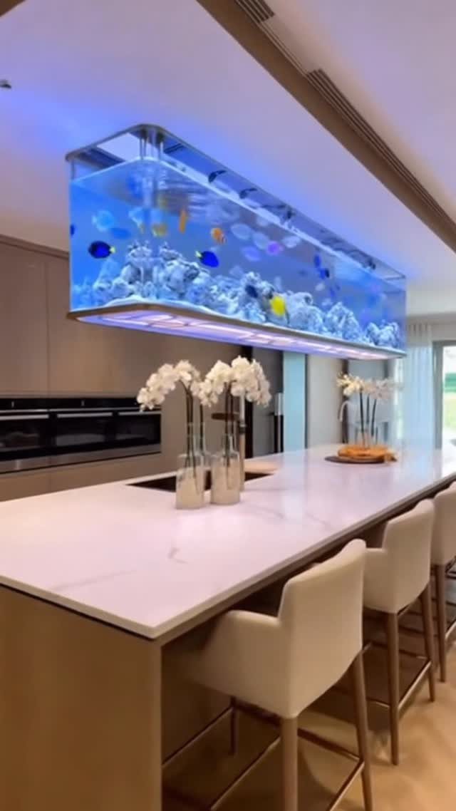 Modern kitchen with a white marble island and a suspended ceiling aquarium.