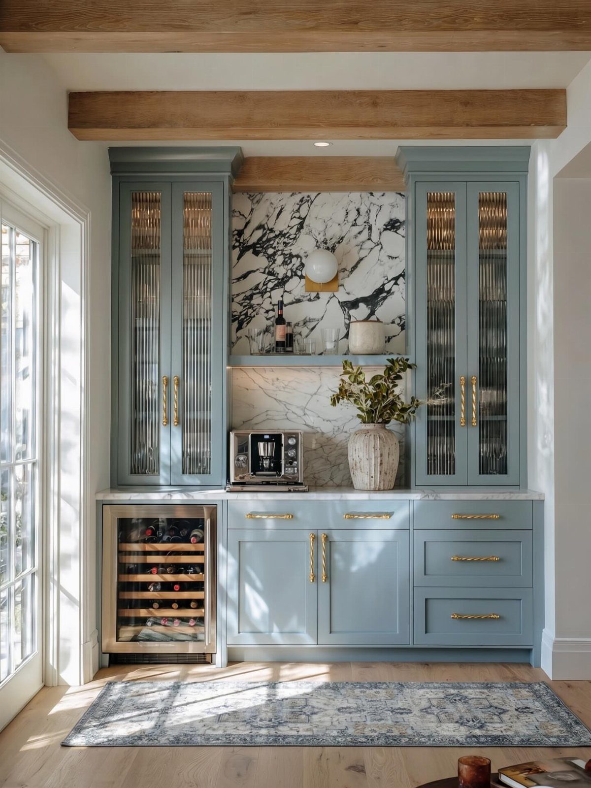 Light blue kitchen cabinetry with gold hardware and a white marble backsplash.