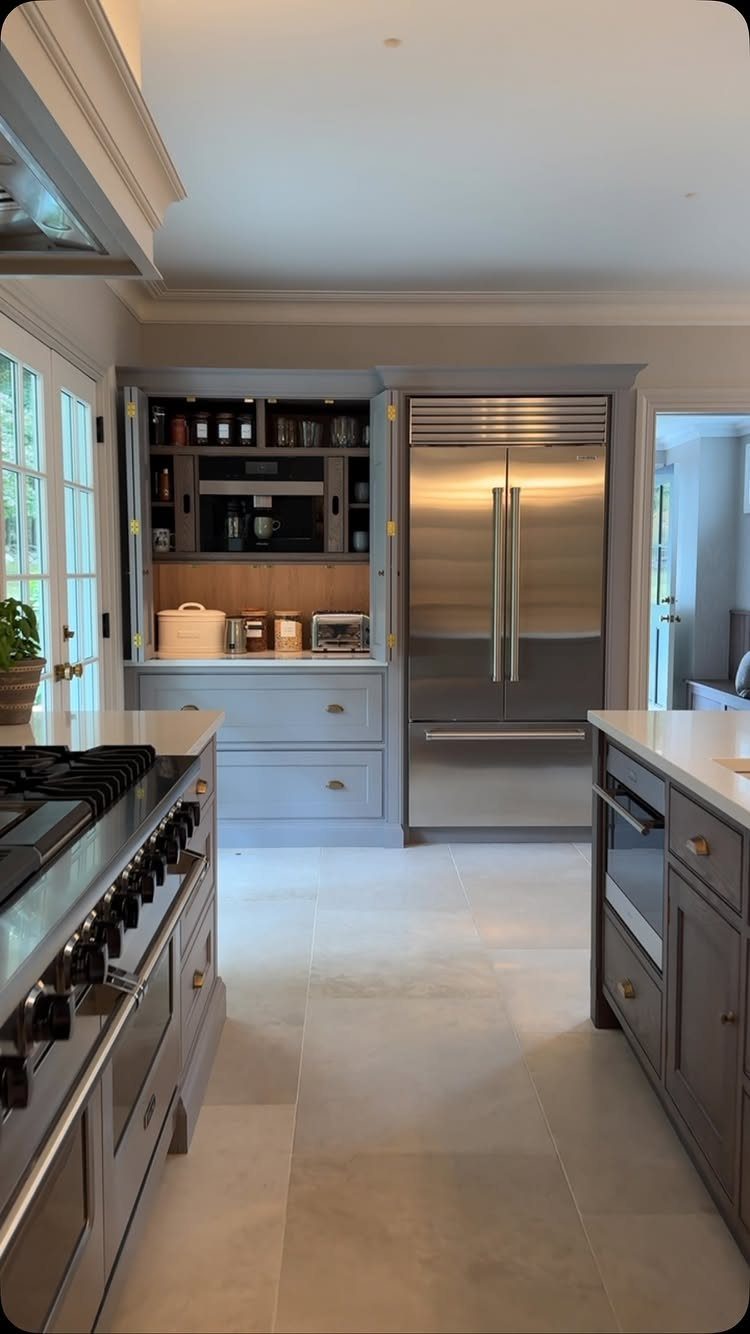 Modern high end kitchen with grey cabinets, stainless steel appliances, and white countertops.