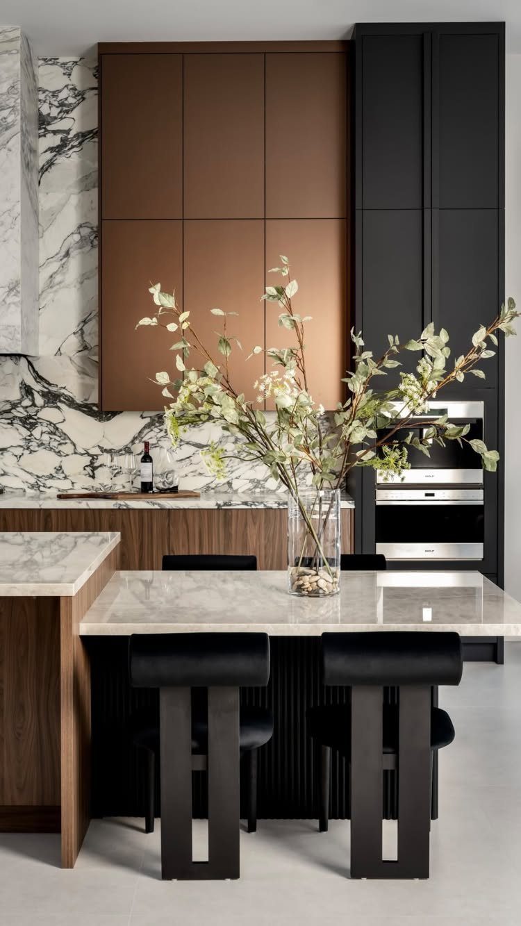White marble kitchen island with black stools and modern brown and black cabinetry