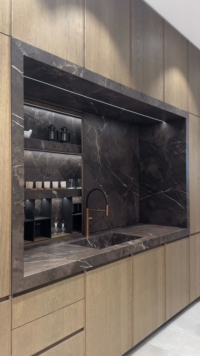 Dark marbled stone countertop and backsplash contrasted with light wood grain cabinetry.