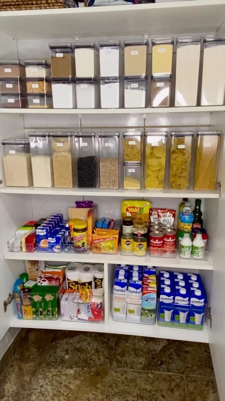 Organized white kitchen cabinets with clear storage containers and neatly arranged pantry staples.