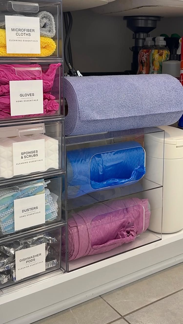 Clear plastic drawers and shelves organizing cleaning supplies under a kitchen sink.