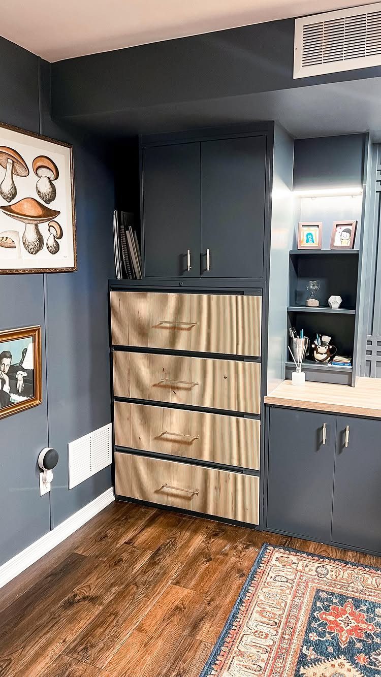 Four-drawer filing cabinet with light wood fronts integrated into dark blue office cabinetry.