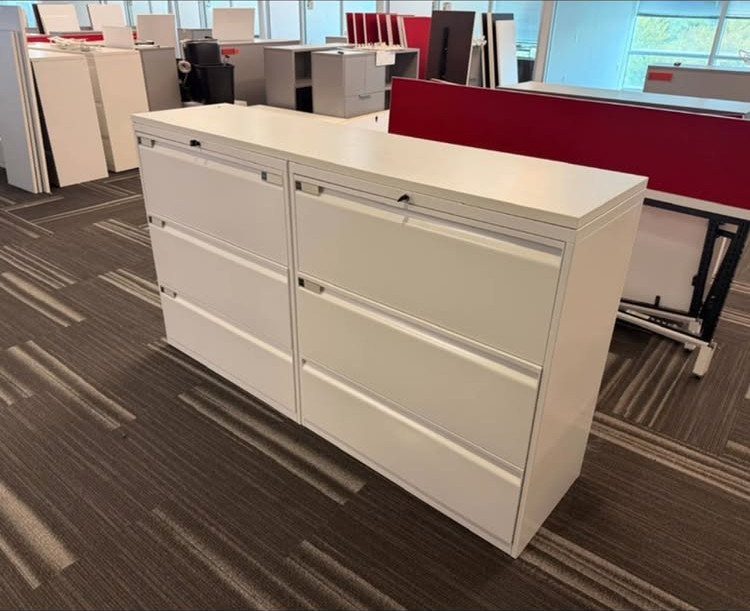 White double-column filing cabinet with a flat top on grey office carpeting.