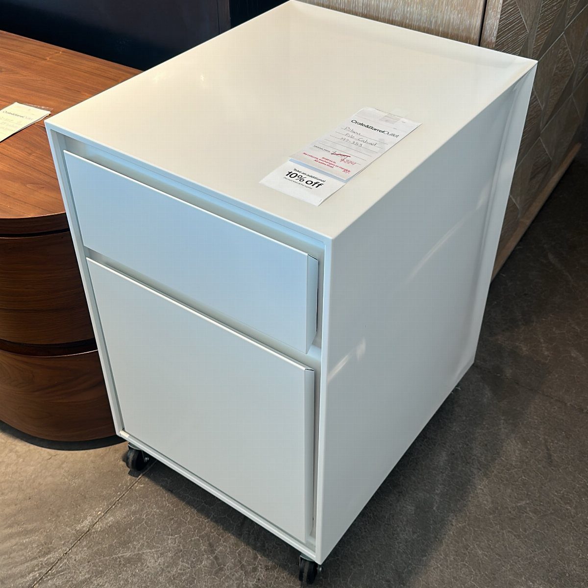 White two-drawer metal filing cabinet on wheels with a price tag on top.