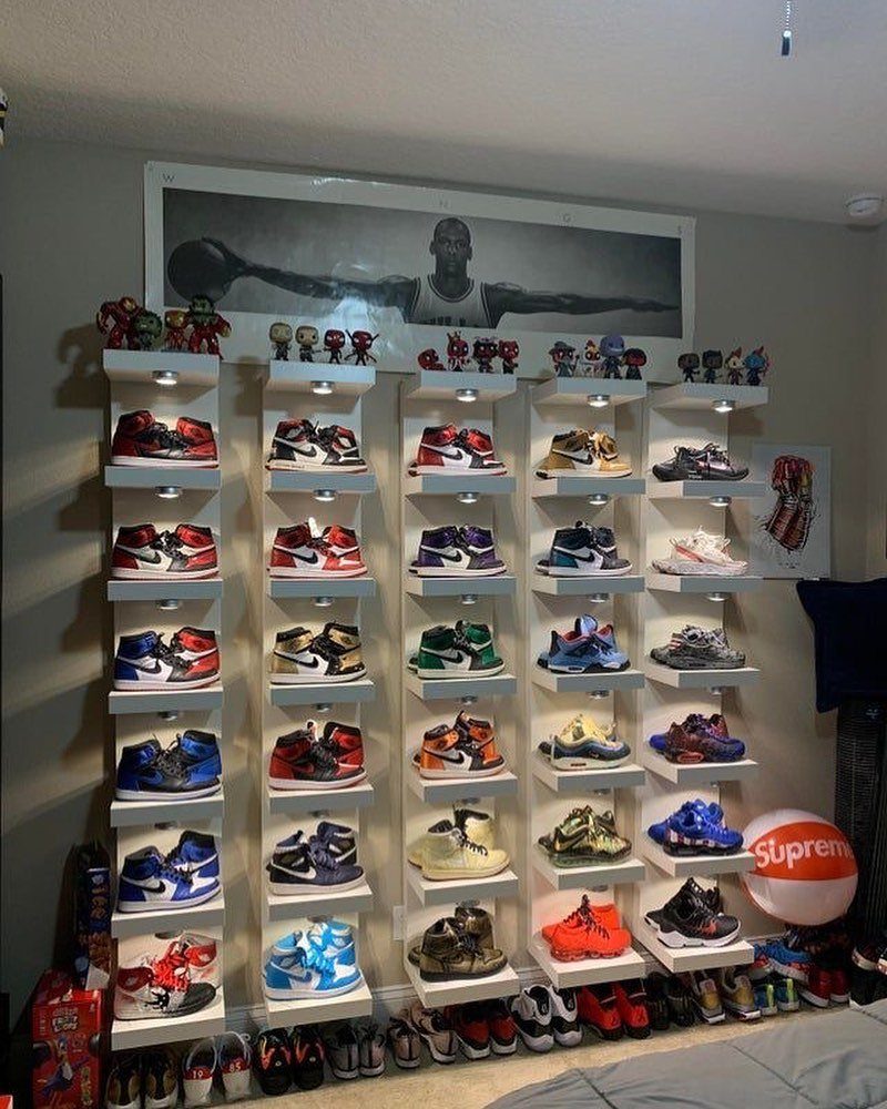 Wall-mounted white shoe display shelves with integrated lighting showcasing a sneaker collection.