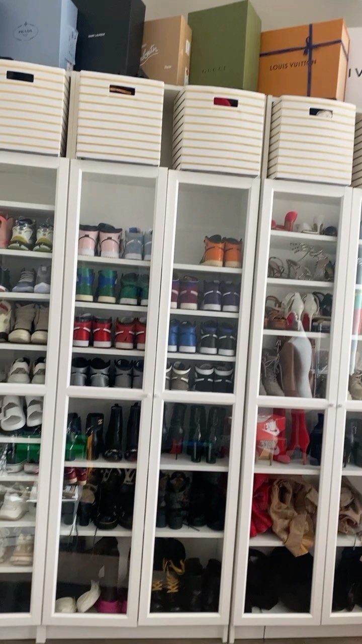 White glass-door shoe cabinets filled with footwear and topped with storage boxes.