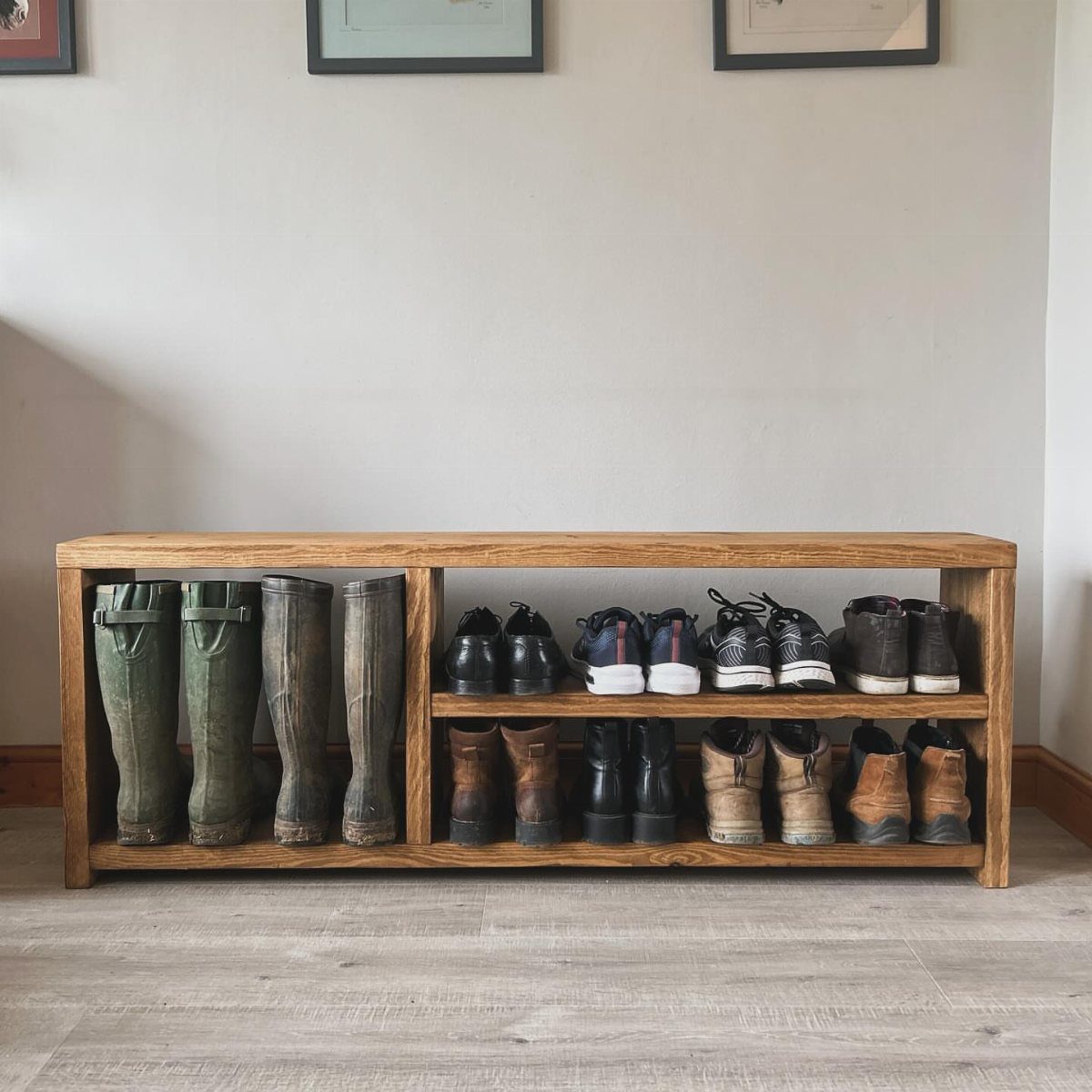 Wooden shoe cabinet with open shelving holding rubber boots and leather footwear.