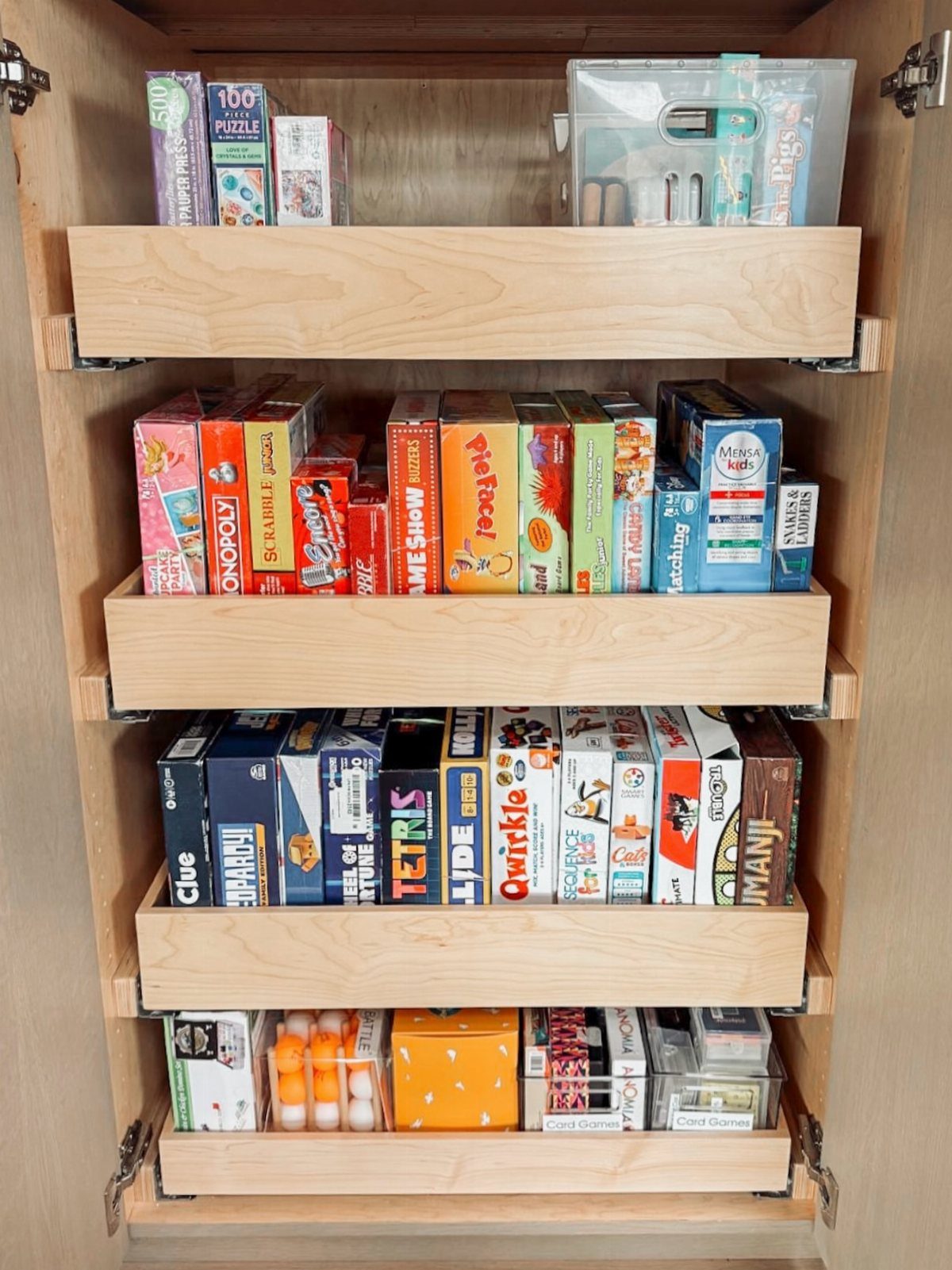 Wooden cabinet drawers filled with colorful board games and puzzle boxes.