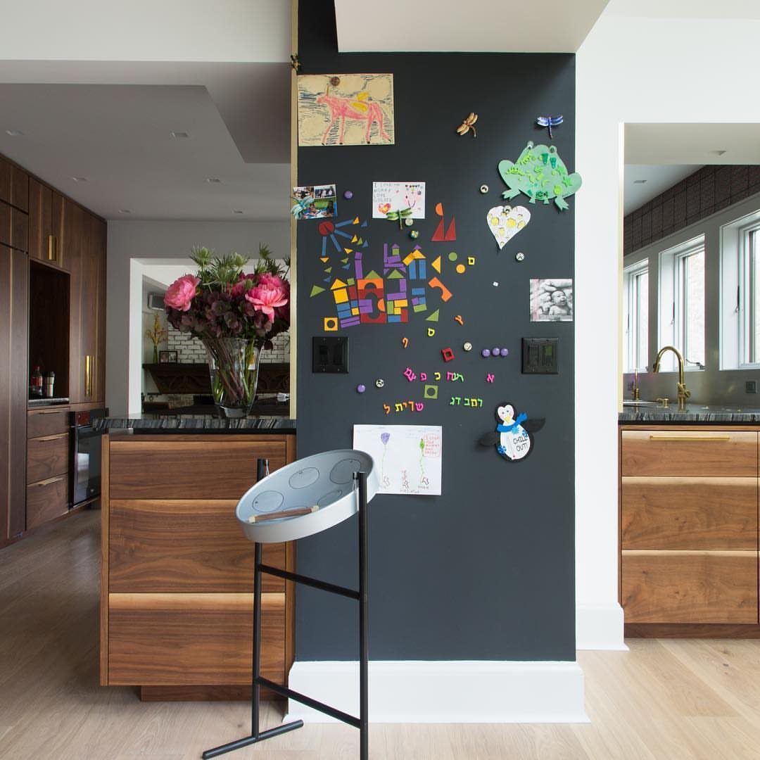 Dark grey chalkboard wall decorated with colorful children's art in a modern kitchen.