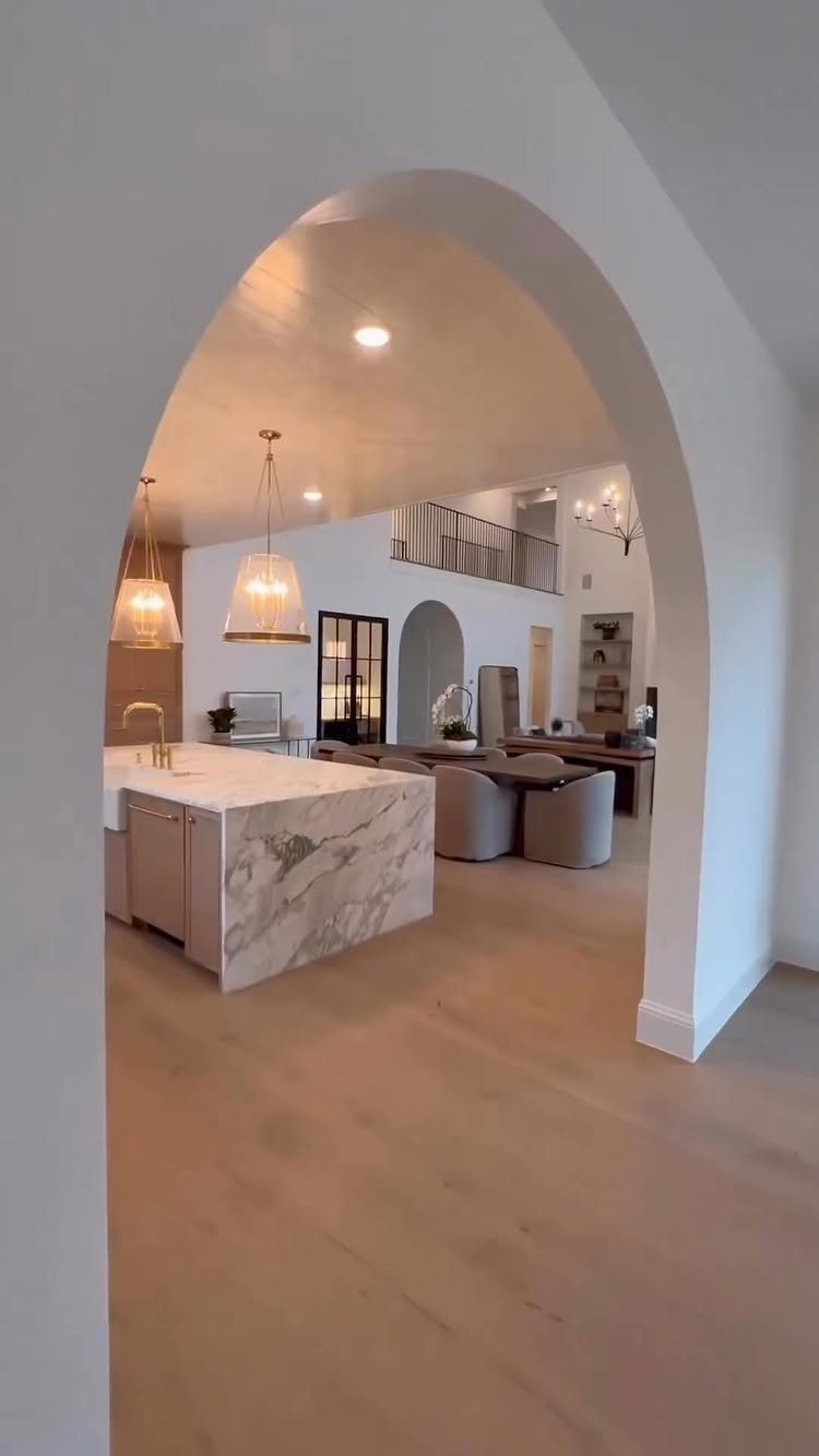 Modern open concept kitchen and dining area seen through a white arched doorway