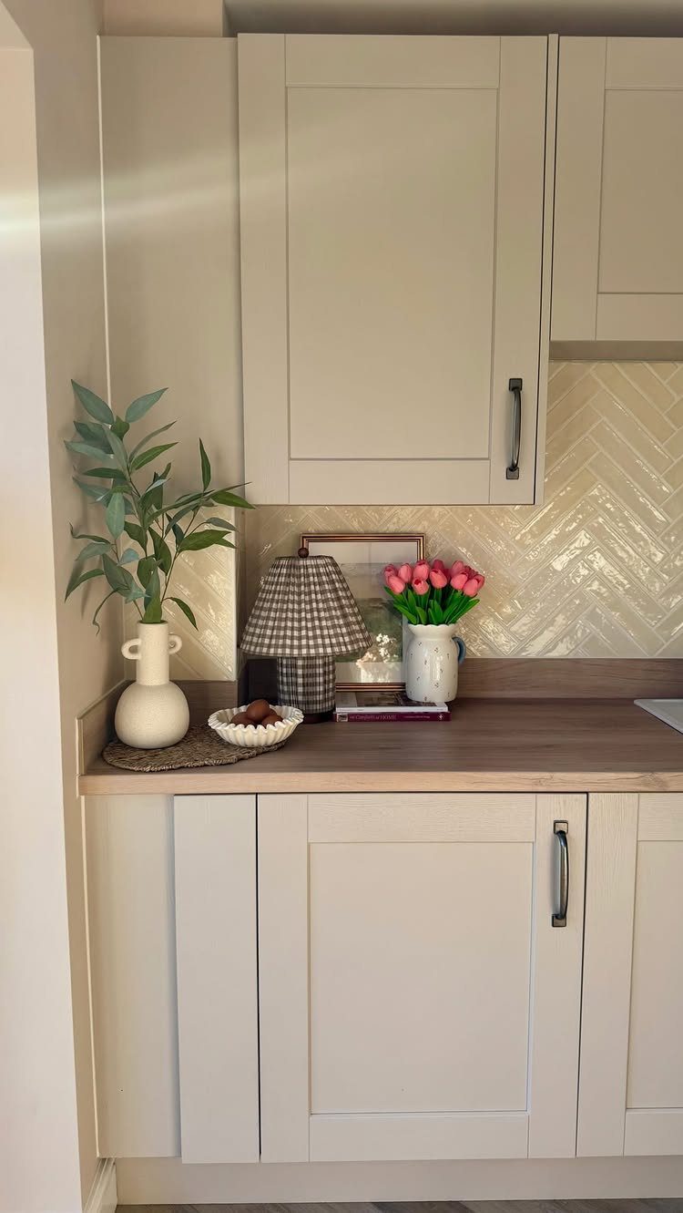 White chevron tile backsplash between white kitchen cabinets and a light wood countertop.