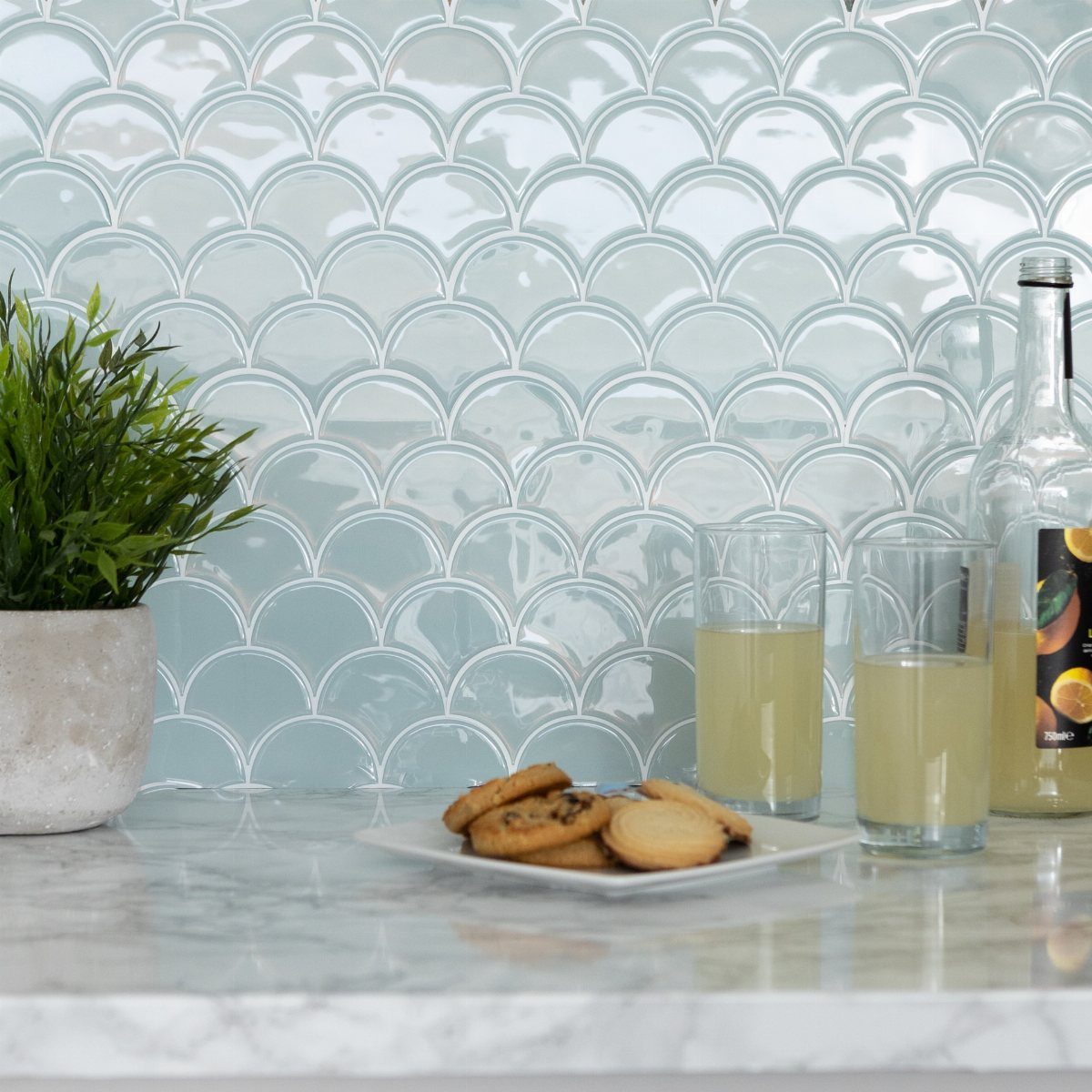Light blue fish scale tiles backsplash with marble countertop, lemonade, and cookies.
