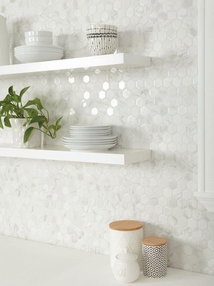 White hexagon mosaic tile backsplash with white floating shelves and kitchen canisters.