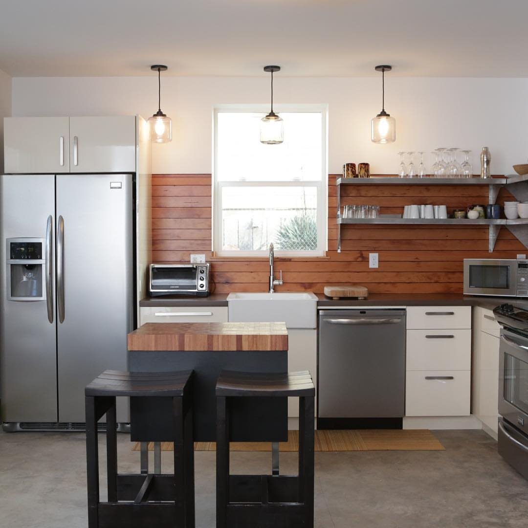 Wooden plank backsplash in a kitchen with white cabinets and stainless steel appliances