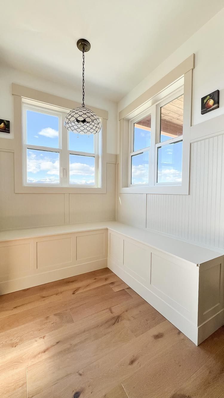 White L-shaped built-in bench in a bright room with light wood flooring.