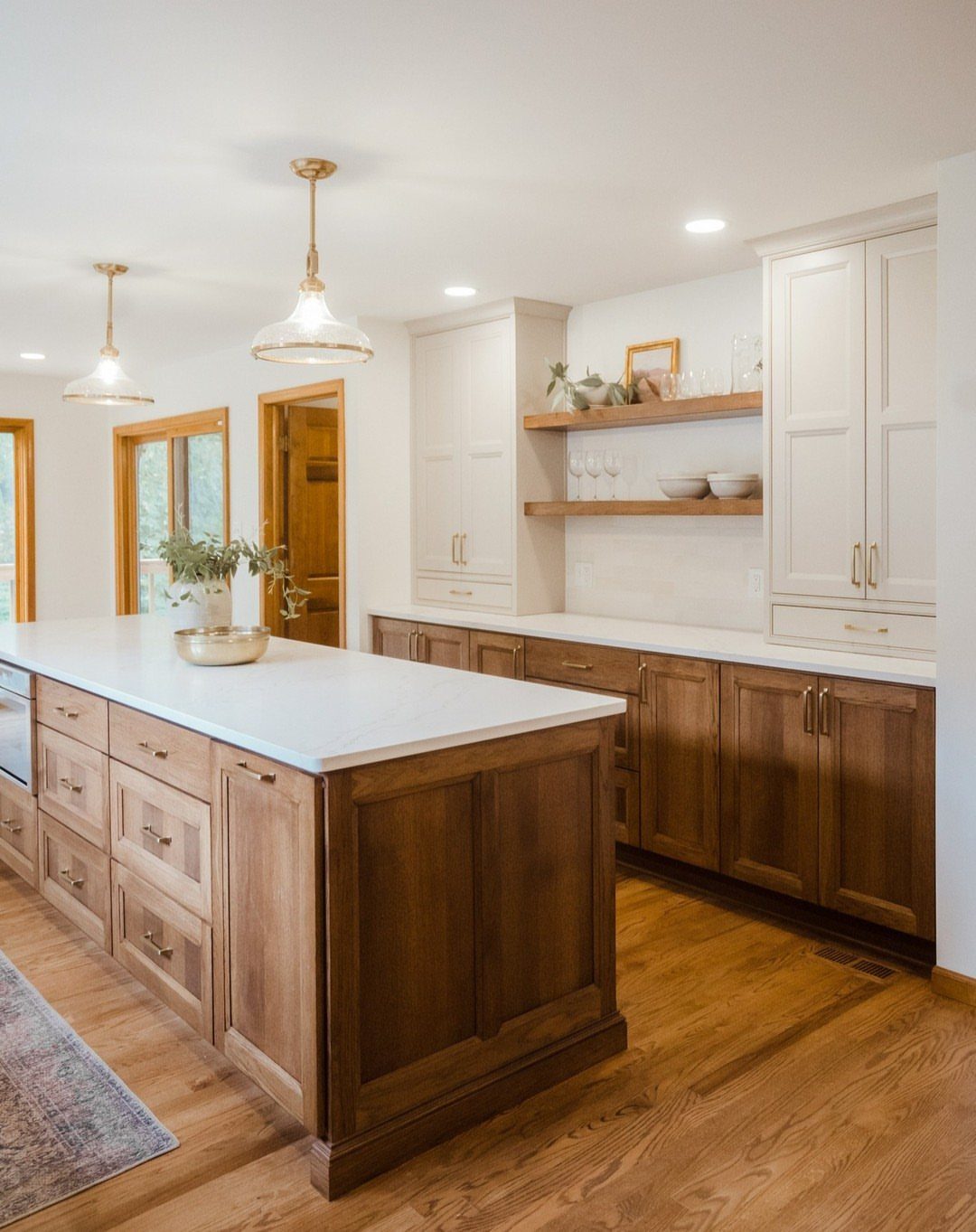 Two-tone kitchen cabinets with white upper units and natural wood lower cabinets and island.