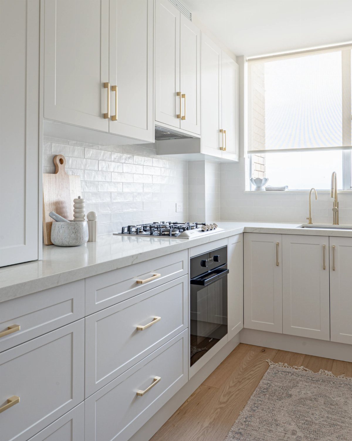 White shaker kitchen cabinets with gold hardware and white subway tile backsplash.