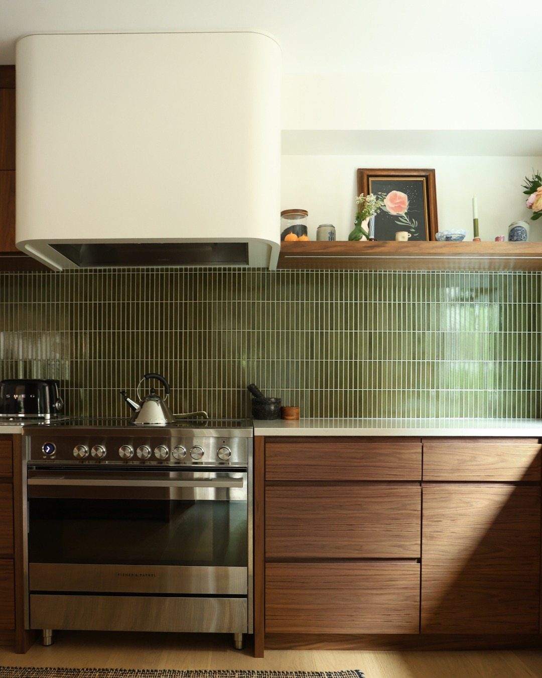 Wood kitchen cabinets with a stainless steel oven and green tiled backsplash.