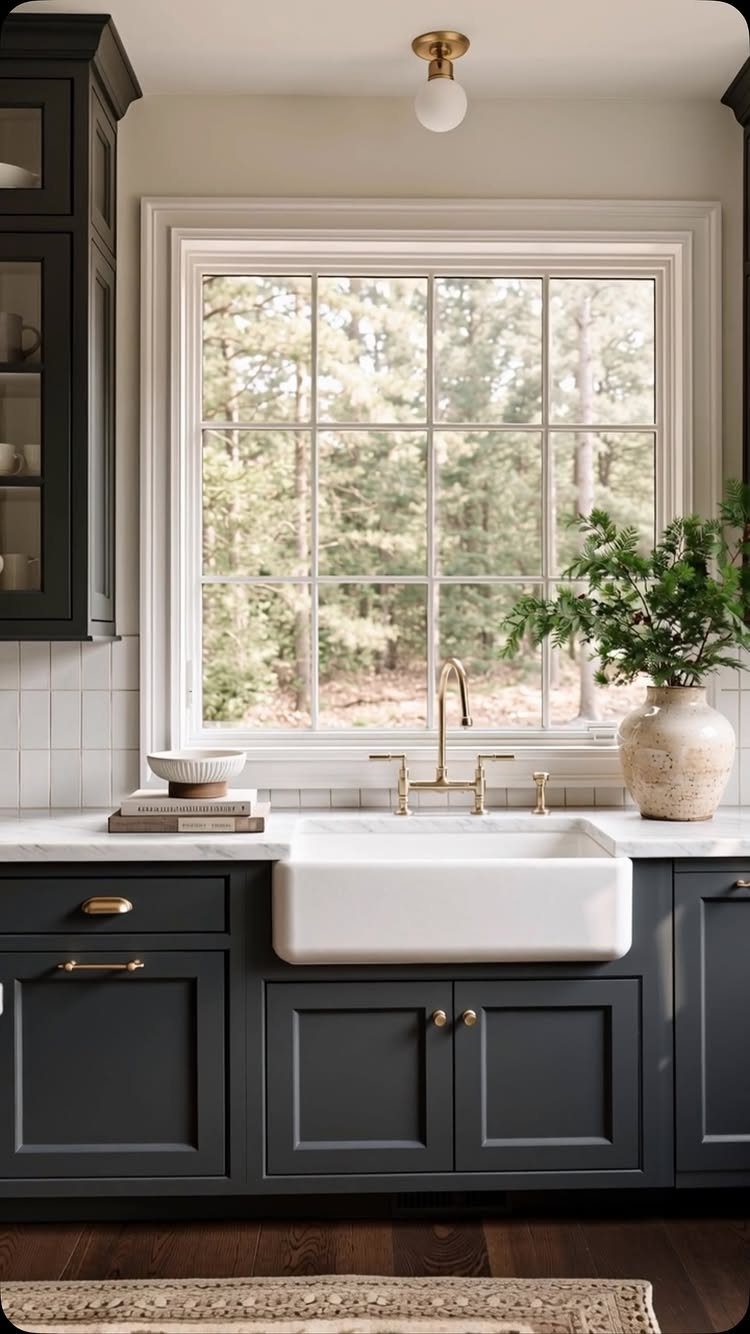 Charcoal gray kitchen cabinets with a white farmhouse sink and gold hardware.