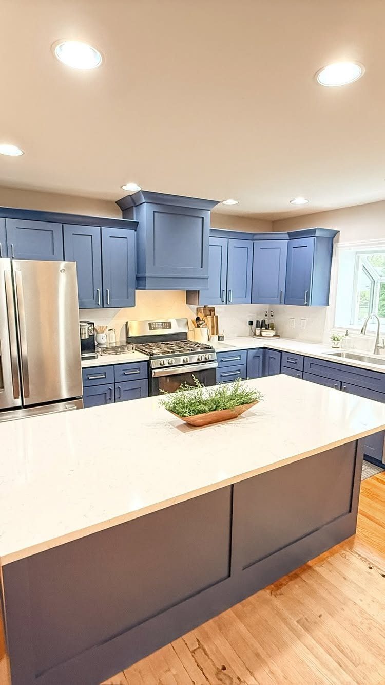 Navy blue kitchen cabinets with white countertops and a large center island.