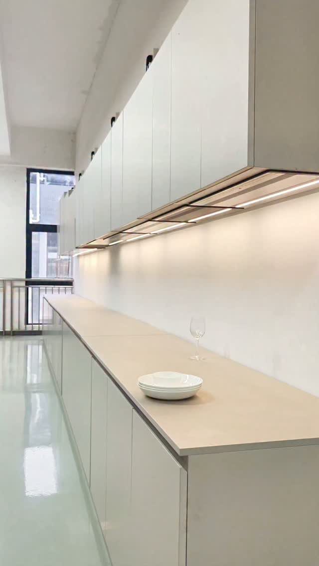 White handleless kitchen cabinets with a light countertop and under-cabinet lighting.