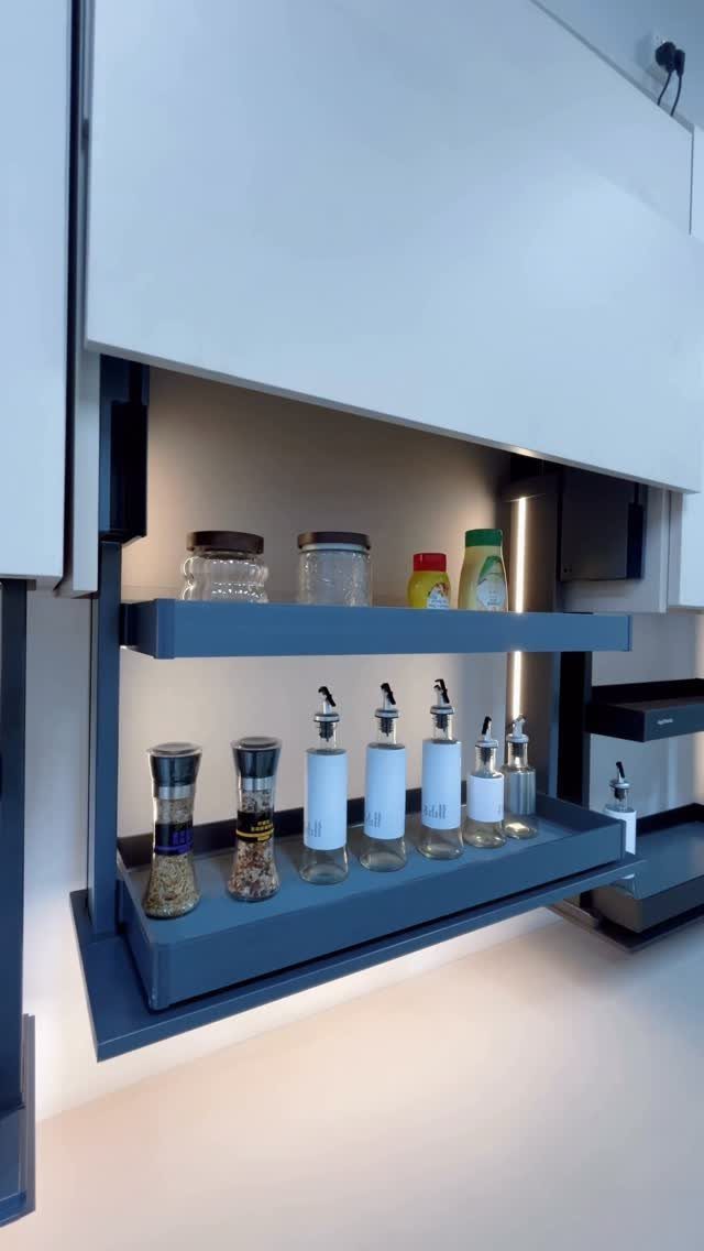 White handleless kitchen cabinets with a blue-grey open shelf holding spice jars.