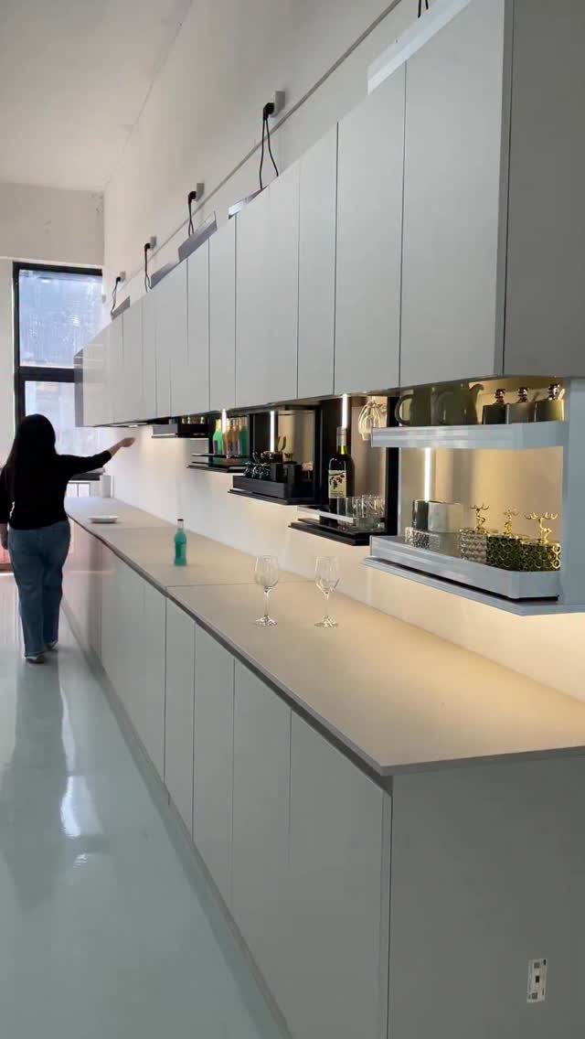 White handleless kitchen cabinets with a person opening an upper cabinet door.