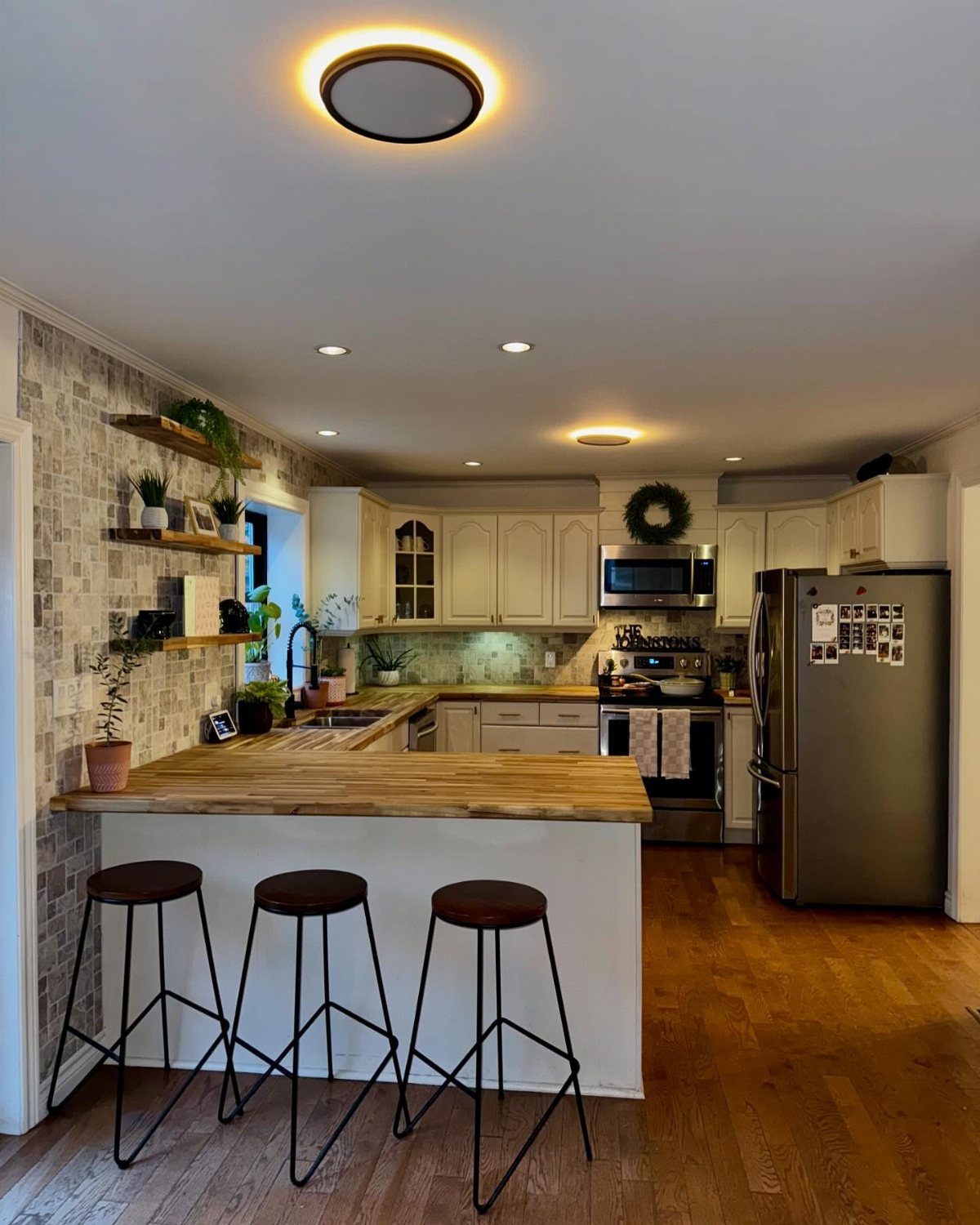 Butcher block countertop on a white kitchen island with black metal bar stools.