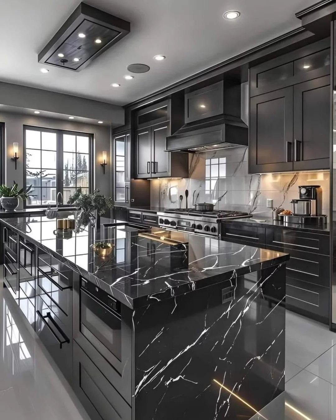 Black kitchen cabinets and a black marble island with white veining and waterfall edge