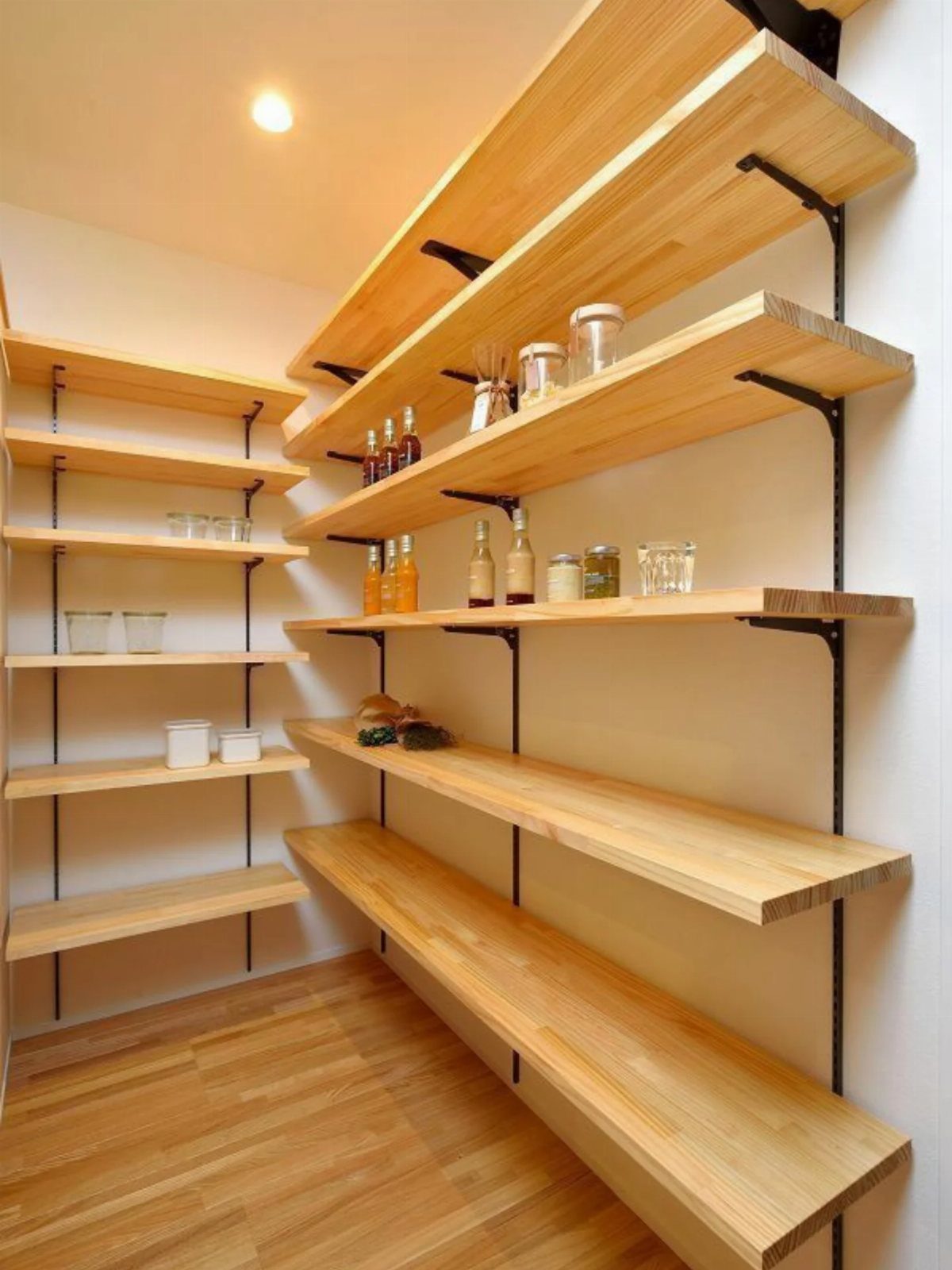Light wood open shelving with black brackets in a white pantry room