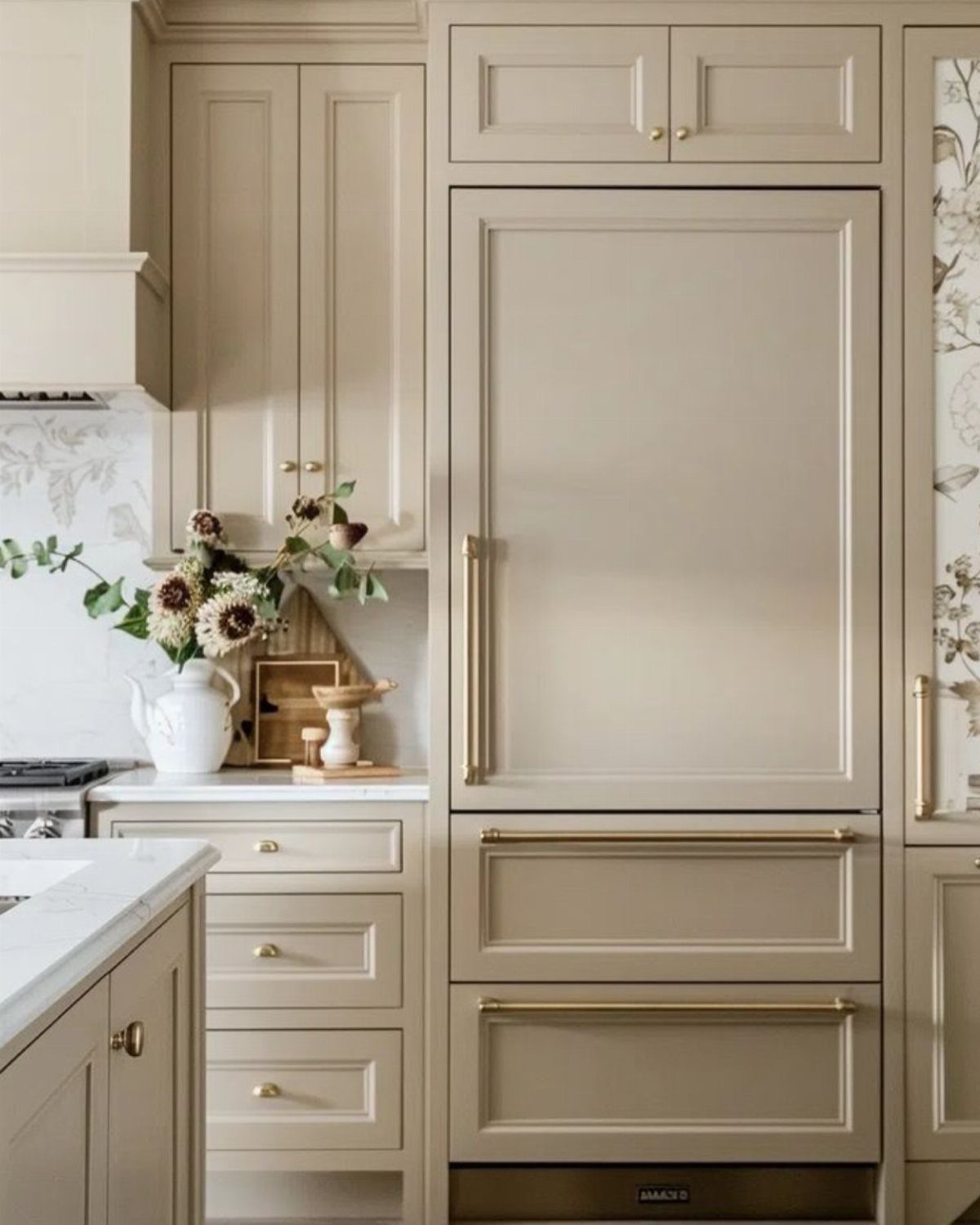 Beige panel-ready refrigerator and freezer integrated into matching kitchen cabinetry with gold handles.