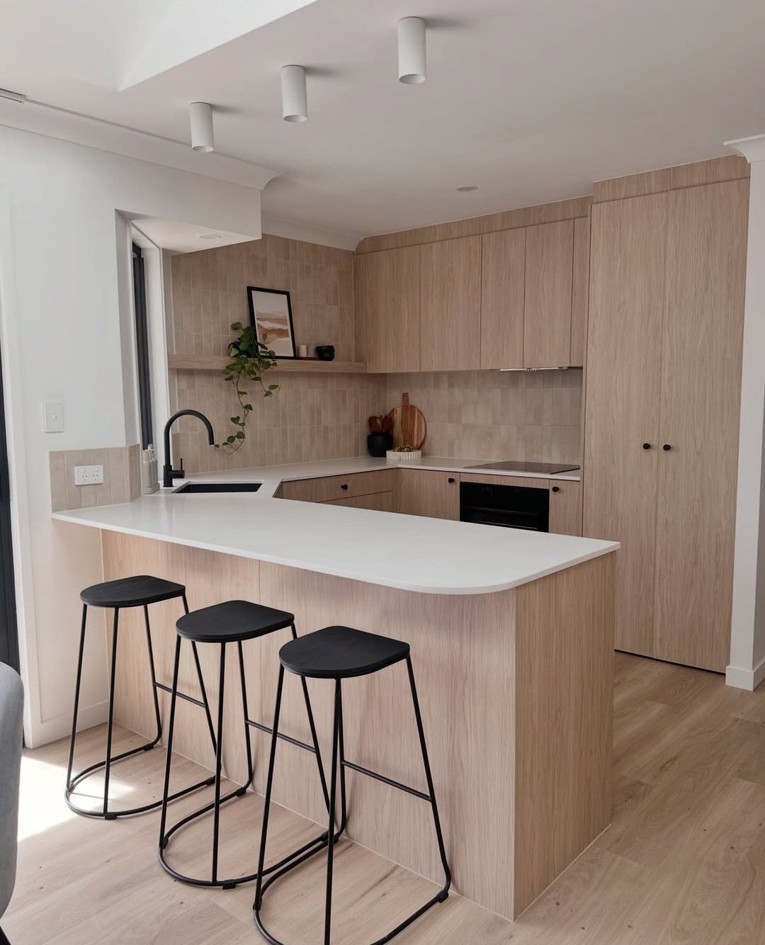 Light wood kitchen cabinets with a white subway tile backsplash and white countertops.
