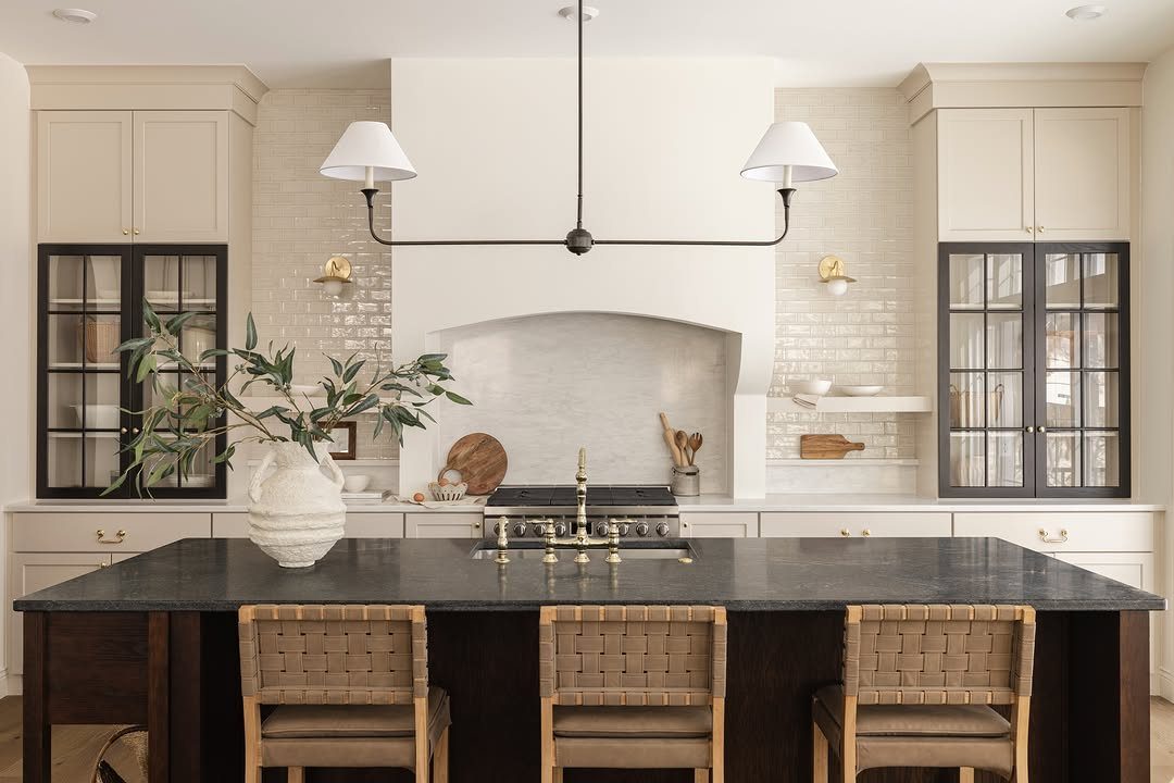 Black countertop kitchen island with woven stools and white cabinetry in the background