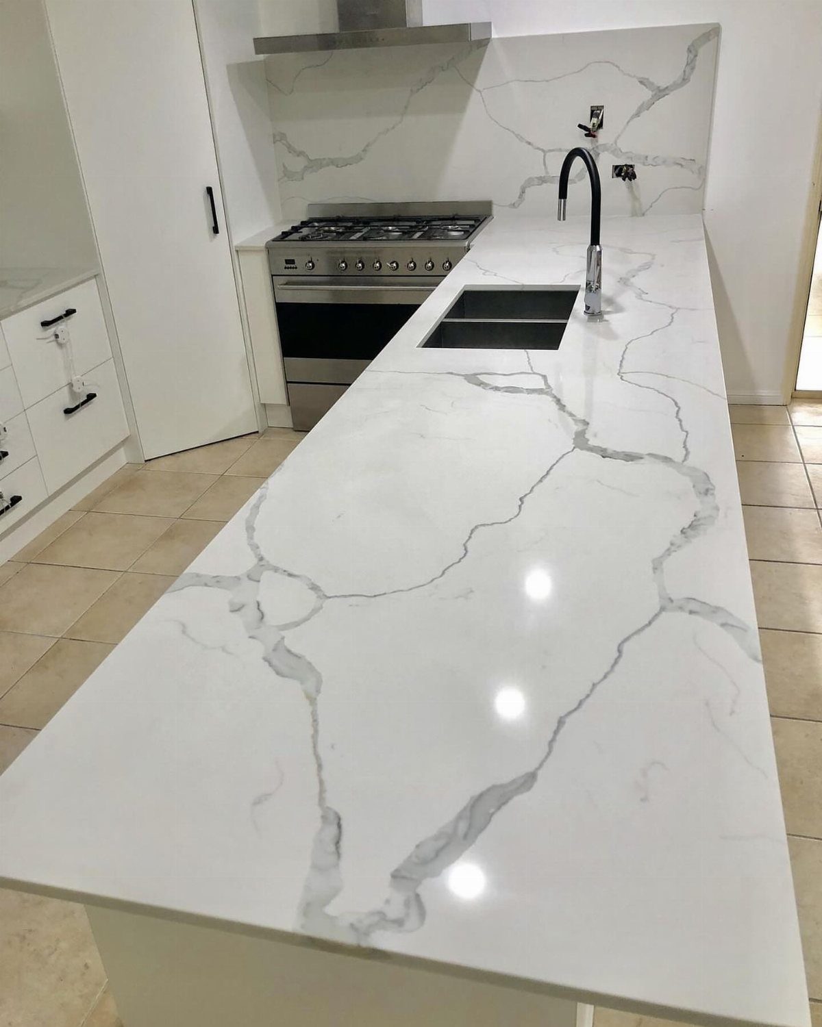 White quartz countertops with grey veining in a modern kitchen with white cabinets.