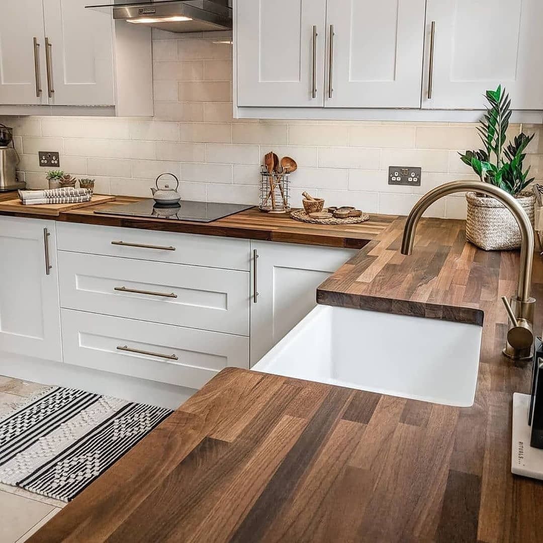 Wood countertops and white cabinets in a bright kitchen with a farmhouse sink.