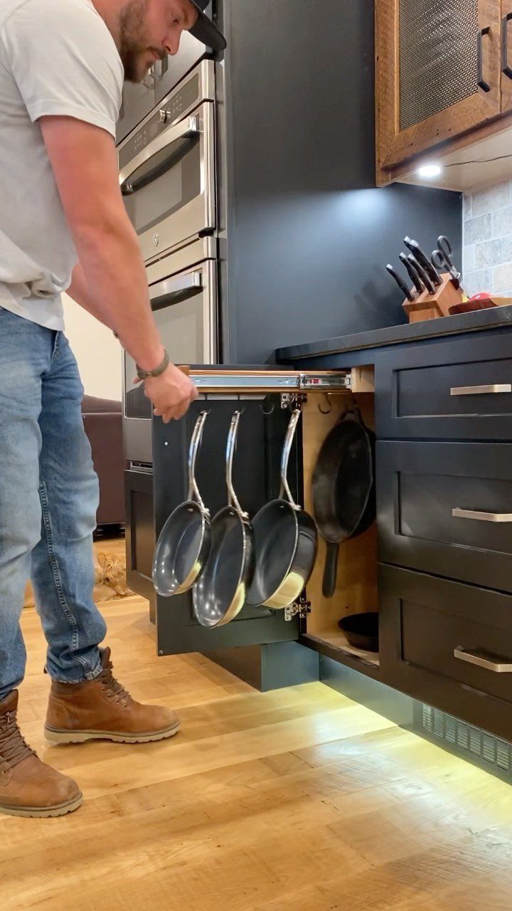 Man opening a black kitchen drawer with a custom pull-out pan organizer.