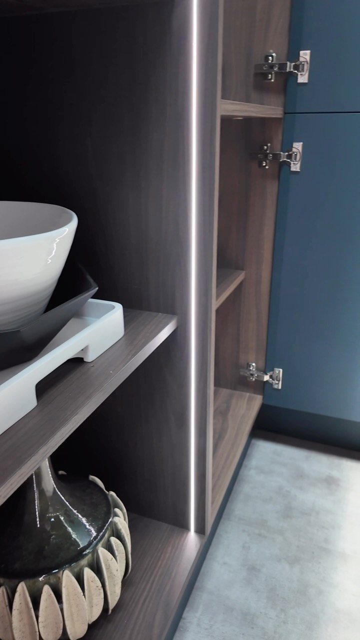 Vertical LED strip lighting integrated into dark wood kitchen shelving with decorative bowls.
