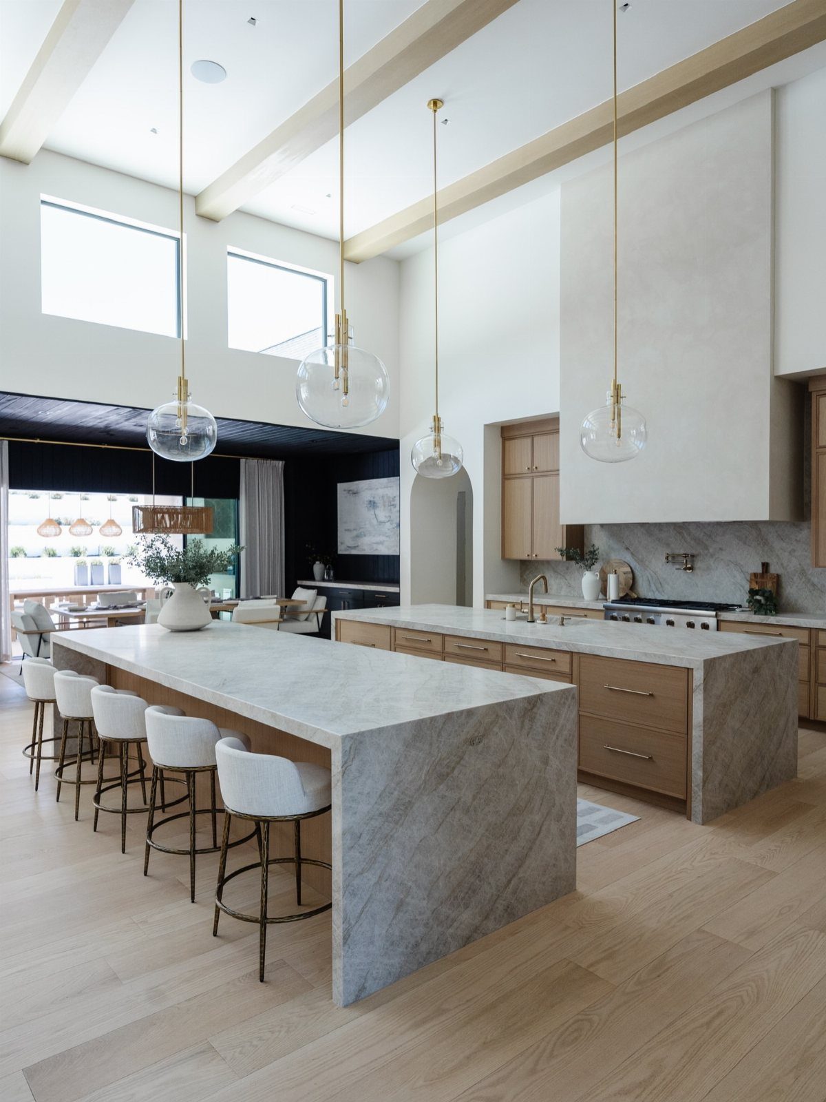 Two parallel marble kitchen islands with white bar stools in a bright modern room