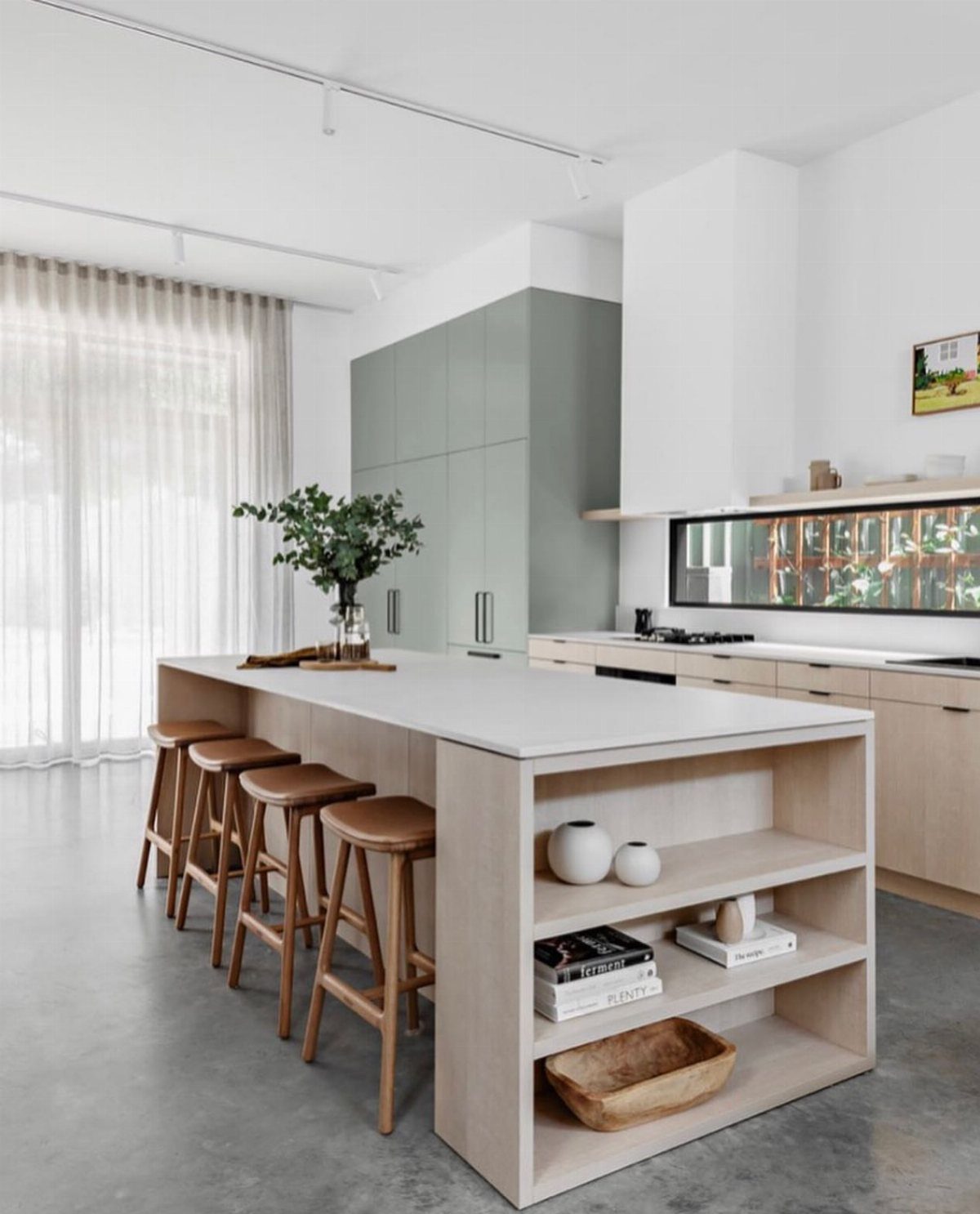 Modern kitchen island with white countertop, wooden stools, and integrated open shelving.