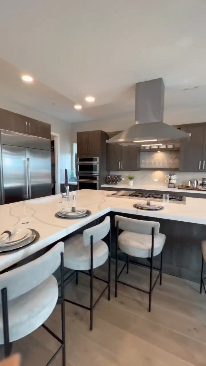 L-shaped kitchen island with white countertops and white upholstered bar stools