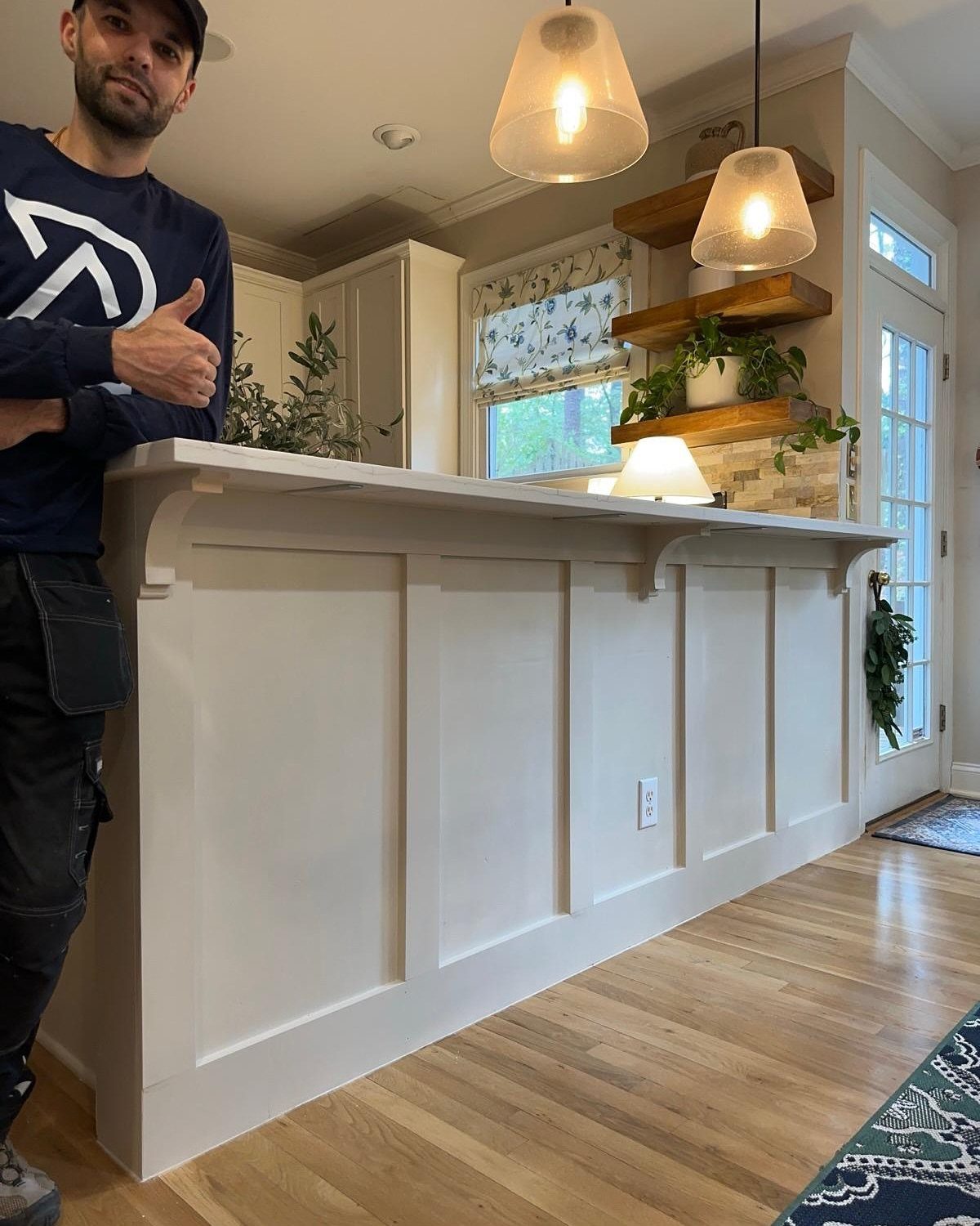 White kitchen island with board and batten paneling and light wood flooring.