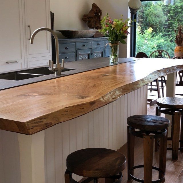 Kitchen island with a live-edge wood top and white beadboard back panel.