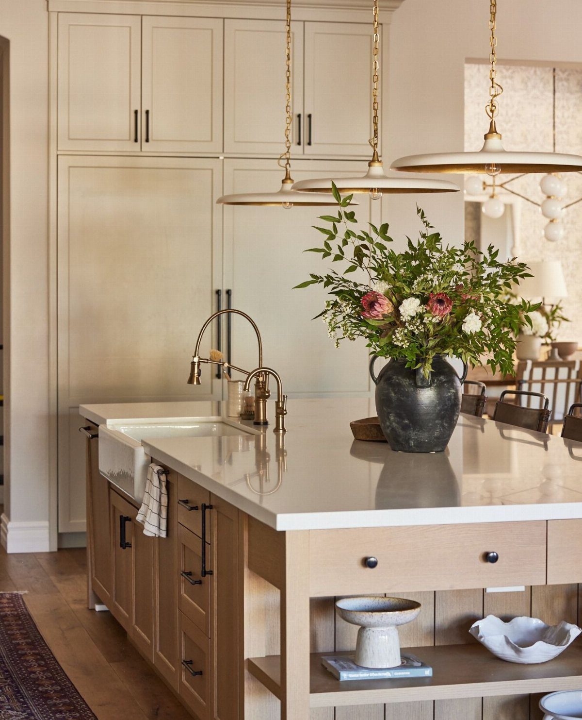 Kitchen island with a white countertop and open wooden shelves holding decorative bowls.