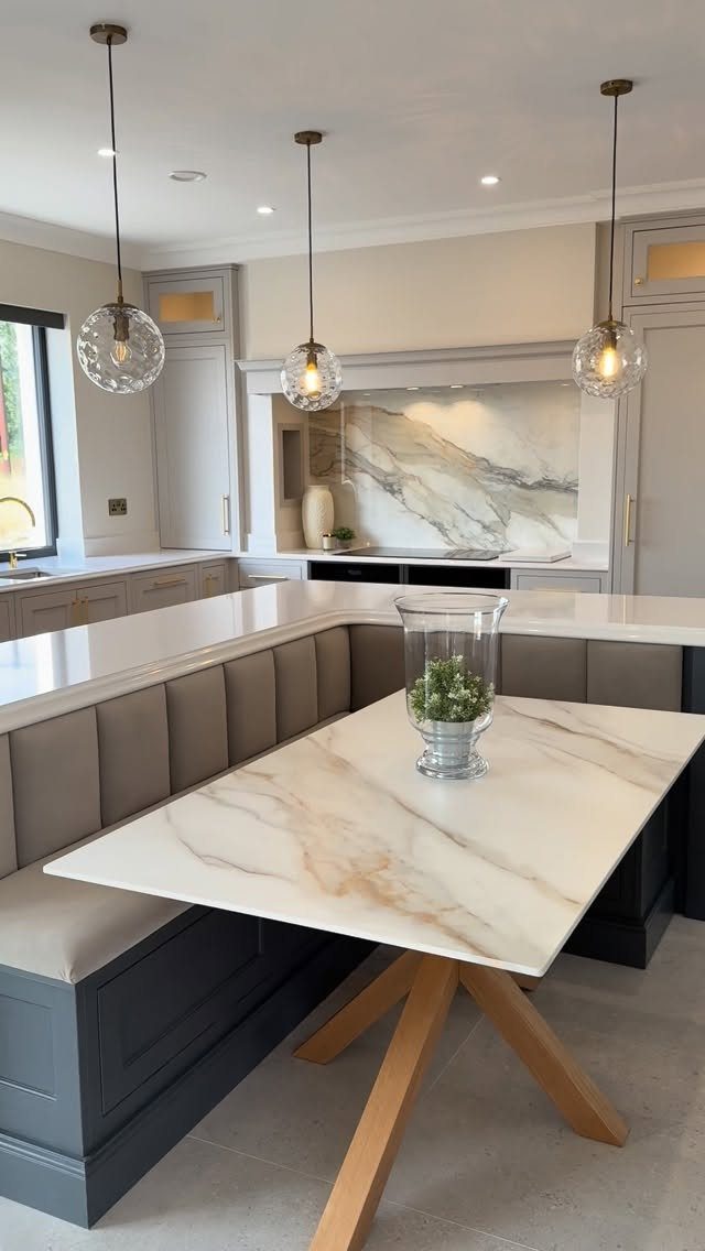 Marble table with a grey L-shaped banquette seat in a modern kitchen
