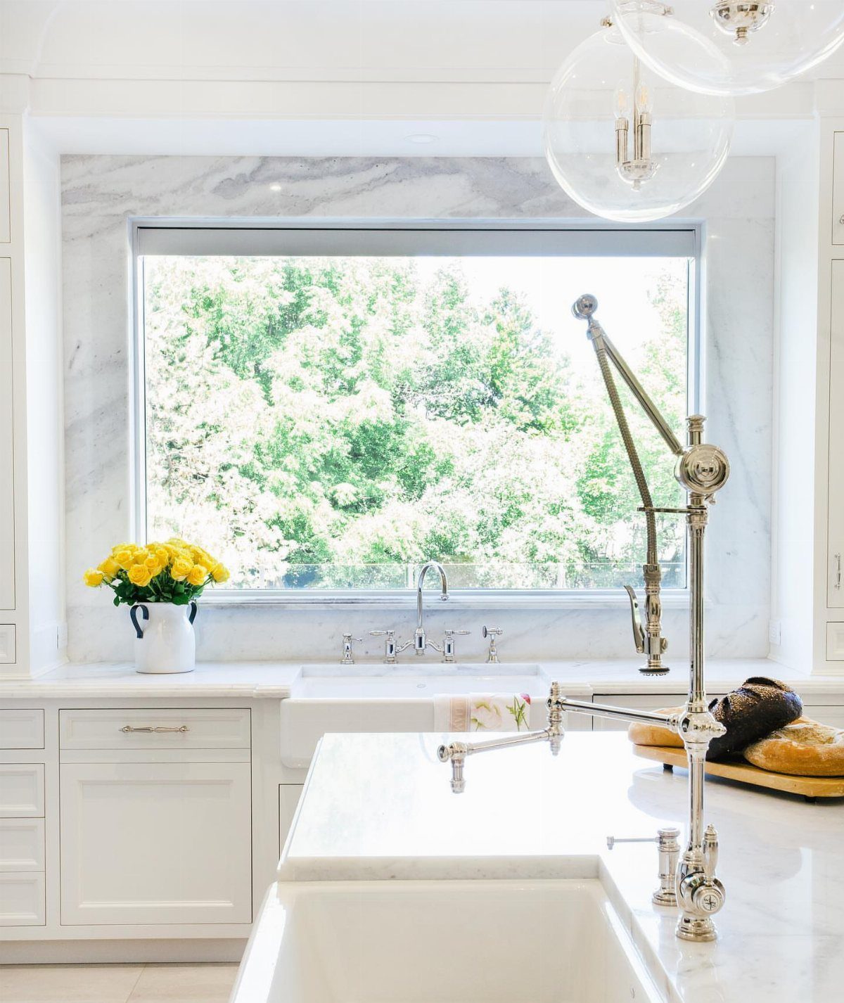 White marble kitchen island with a white sink and ornate silver faucet.